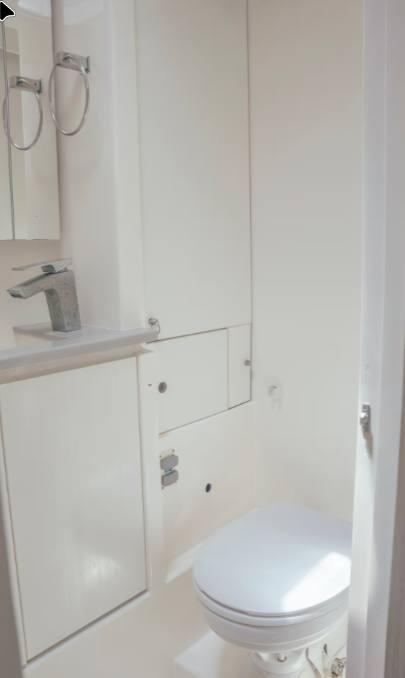 A clean private head with electric-flush toilet, basin and mirror