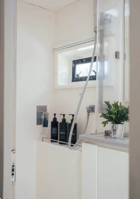 A private bathroom with a hot shower, toiletries and a leafy plant by the window