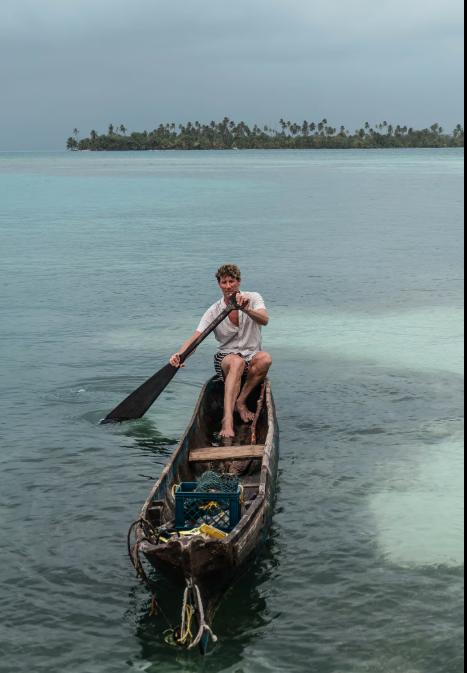 A crew member holding two fresh fish over the water