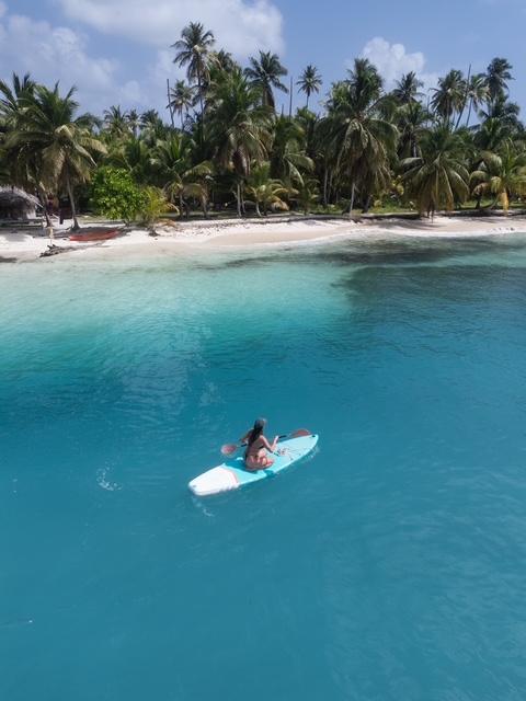 A guest paddleboarding across a turquoise lagoon