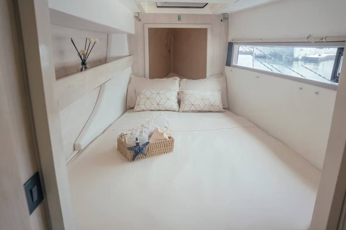 A bright forward double cabin with crisp white linens and a sea-view window