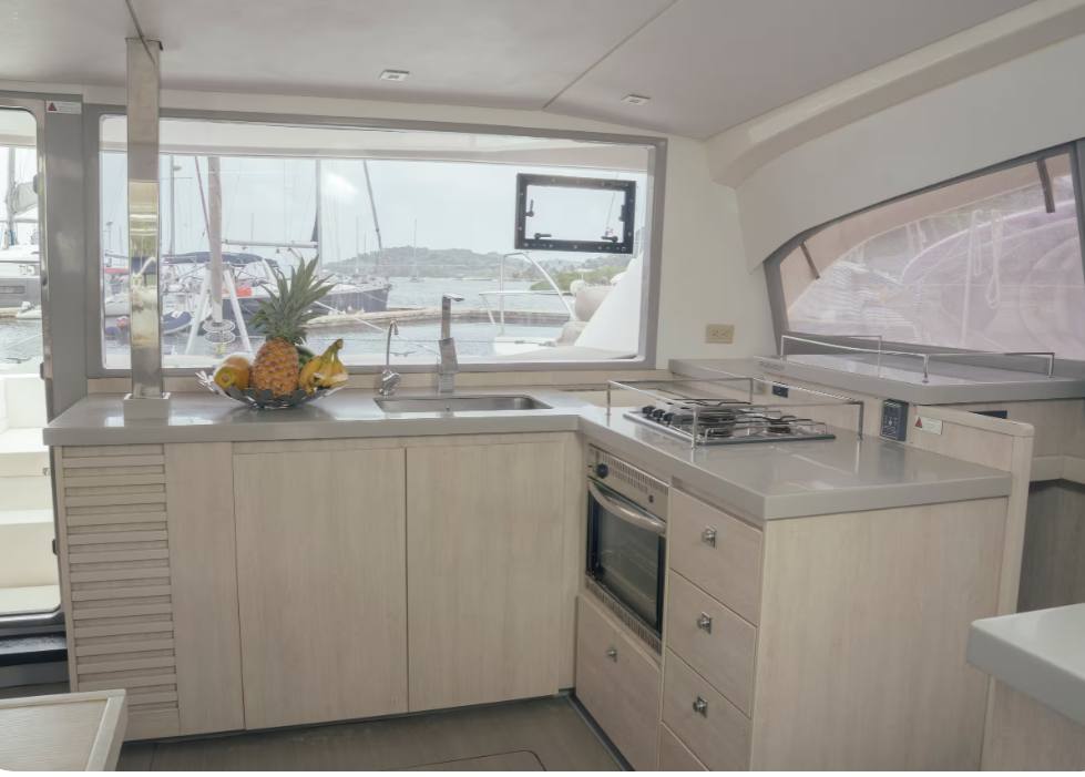 The bright galley with a gas hob, oven and a fruit bowl by the marina-view window