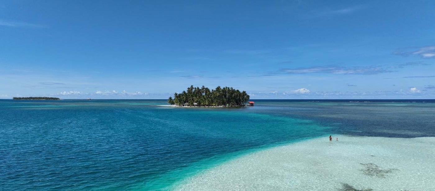 A tiny palm island across a white sandbar
